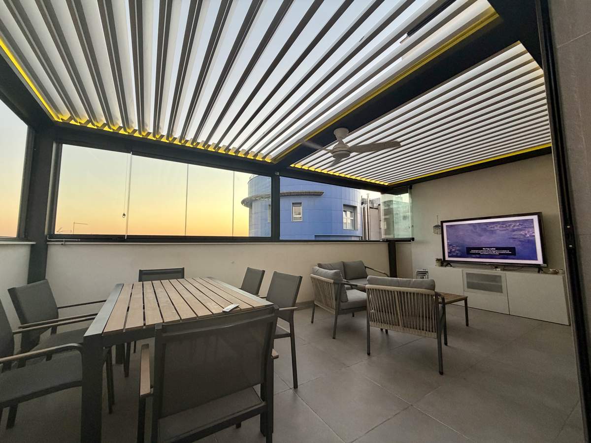 Pérgola bioclimática con cerramiento de cristal y mobiliario moderno