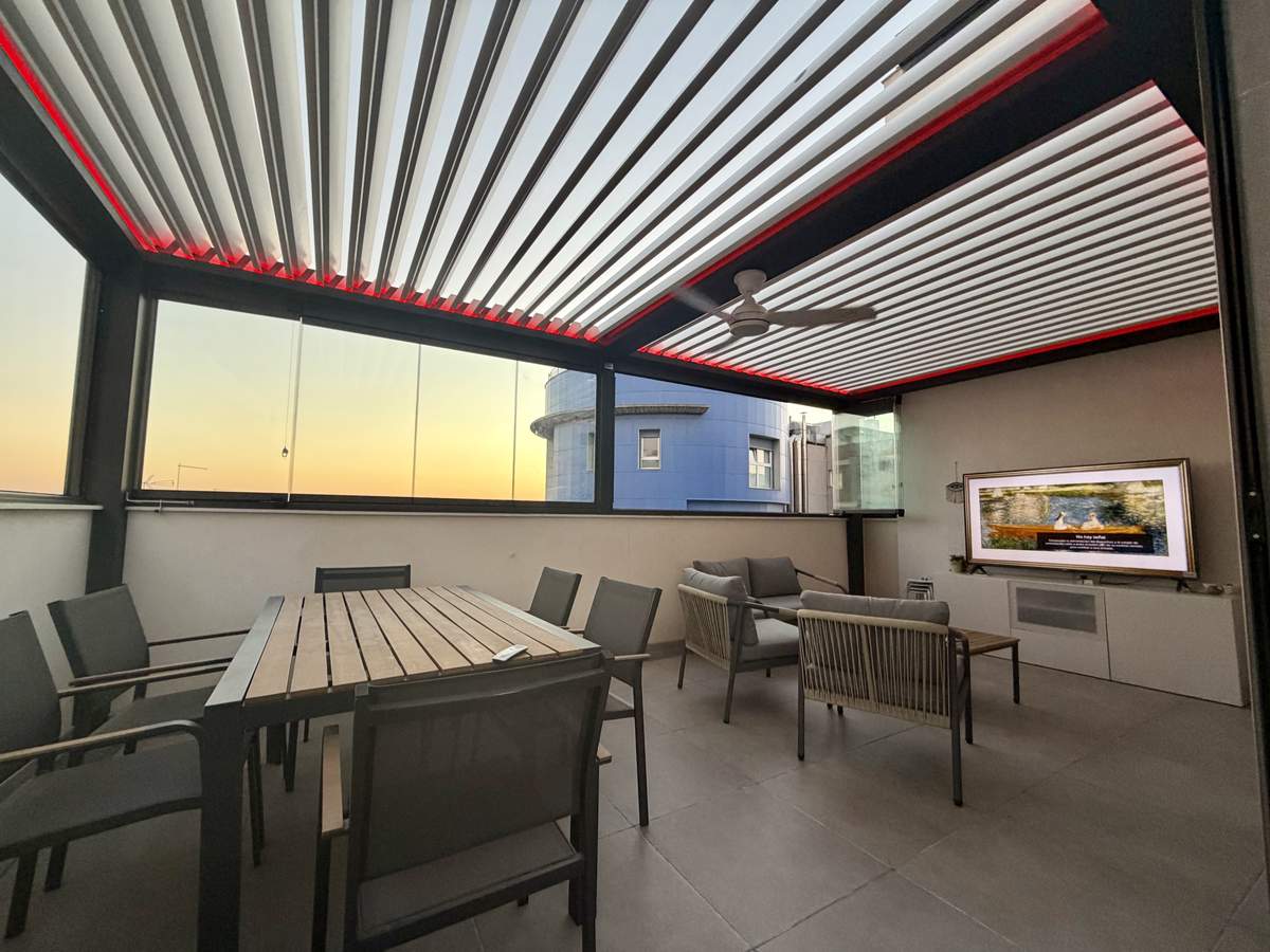 Terraza de ático convertida en salón exterior con pérgola bioclimática