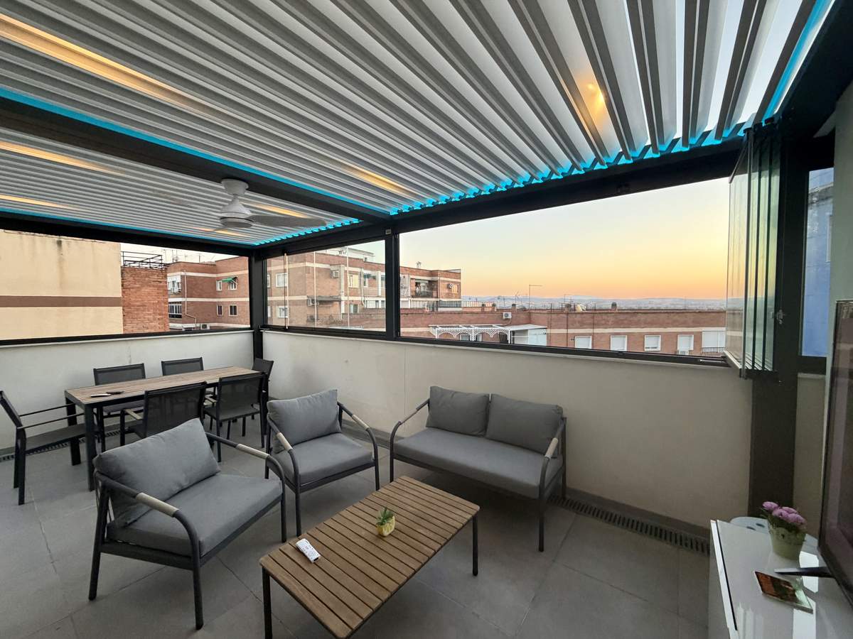 Terraza convertida en habitáculo con pérgola bioclimática y cortinas de cristal