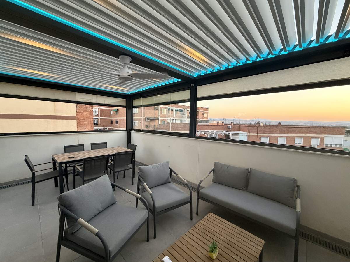 Zona de comedor bajo la pérgola bioclimática con iluminación LED perimetral